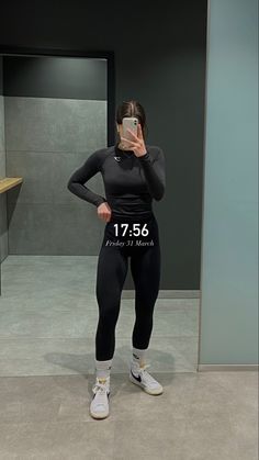 a woman taking a selfie in front of a mirror wearing leggings and sneakers