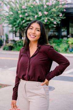 a woman standing on the sidewalk with her hands on her hips and smiling at the camera