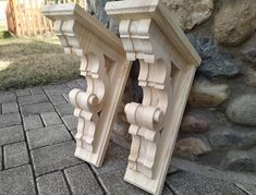 two wooden brackets on the ground next to a stone wall