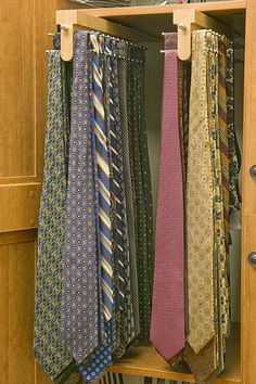 several ties are hanging in a wooden cabinet