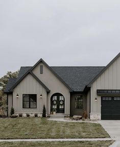 a gray house with black garage doors and windows