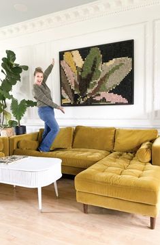 a man jumping up in the air near a couch and table with a plant on it