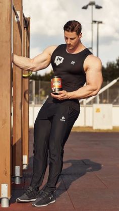 a man leaning against a wooden structure holding a can