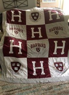 a blanket that is sitting on top of a couch with harvard letters all over it