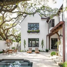 a house with a pool in front of it and chairs on the patio next to it