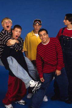 the young men are posing for a group photo in front of a blue background with their mouths open