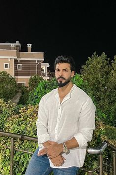 a man in white shirt and jeans leaning on railing