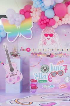 a birthday party with balloons and decorations on the wall, including a pink guitar cake