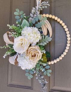 a wreath is hanging on the front door with flowers and greenery around it,