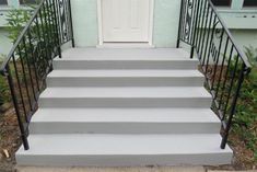 a set of stairs leading up to a white door with wrought iron railings and handrails