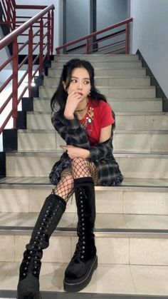 a woman sitting on the steps with her legs crossed wearing black boots and fishnet stockings