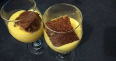 two glasses filled with dessert sitting on top of a table