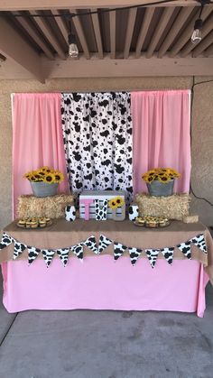 a table topped with hay bales and sunflowers next to a pink curtain