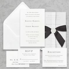 an elegant wedding suite with black ribbon and white paper is displayed on a gray background