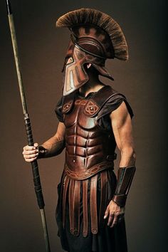 a man dressed in roman armor holding a spear and wearing a helmet on his head