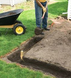 a man with a wheelbarrow digging dirt into a hole in the ground for landscaping