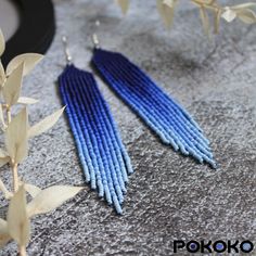 two pairs of blue and white beaded earrings sitting on top of a gray surface