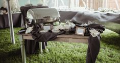 an outdoor table is set up with black linens and silverware for guests to eat