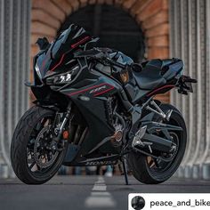 a black motorcycle parked in front of a building with columns and arches on the sides