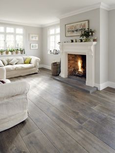 a living room with wood floors and a fire place in the center, on instagram