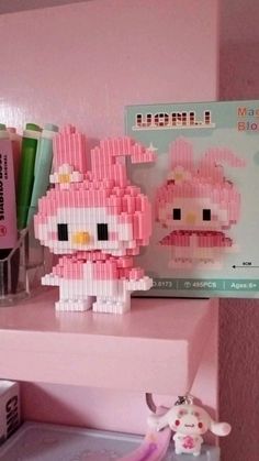 a hello kitty doll sitting on top of a pink shelf next to a toothbrush