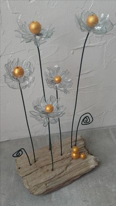 some glass flowers are sitting on a piece of wood and have gold balls in them