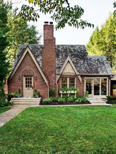 a brick house with green grass and trees