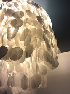 a lamp that is on top of a white table with black and grey circles hanging from it's sides