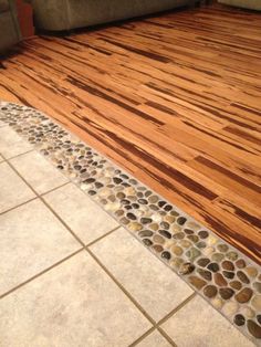 a living room with wood flooring and tile on the floor next to a couch