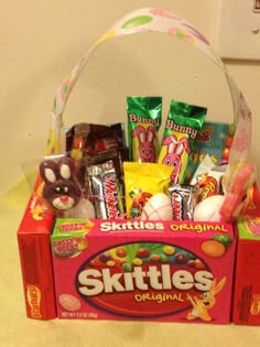 an assortment of skittle's candy and candies in a pink basket on a counter