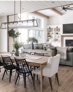 a living room and dining area with wood flooring, white walls and ceiling beams