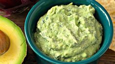 guacamole and tortilla chips on a wooden table with an onion