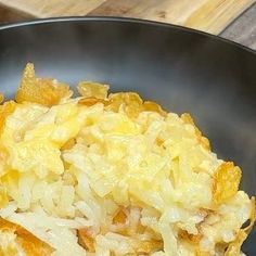 a close up of food in a pan on a wooden table with utensils