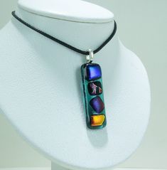 a necklace on a mannequin is decorated with colorful glass beads and black cord