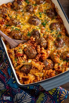 a casserole dish with meatballs and pasta in it on a colorful cloth