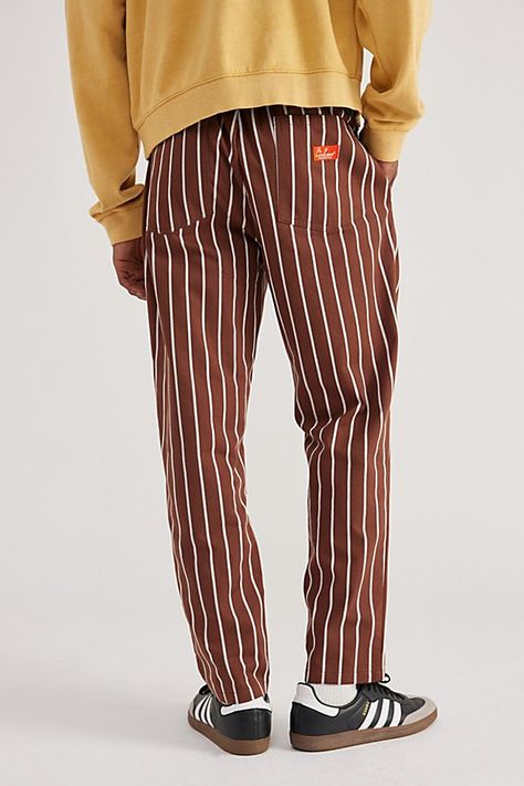 Striped woven chef pants by Cookman. Easygoing woven pants from Cookman feature a relaxed leg, drawstring waist and pockets at the front and back, in a striped pattern. Features Striped woven chef pant from Cookman Drawstring waist 2 front pocket; 2 back pocket Content + Care 65% Polyester, 35% cotton Machine wash Imported Size + Fit Model is 6’1" and wearing size Medium Measurements taken from size Medium Rise: 11" Inseam: 30" Leg opening: 7" | Cookman Striped Woven Chef Pant in Stripe Brown, M Casual Striped Pants For Streetwear, Striped Cotton Pants For Streetwear, Railroad Stripe Pants, Streetwear Cotton Pants With Side Stripes, Luxury Striped Pants, Chef Pants, Drawstring Waist, Urban Outfitters, Fitness Models