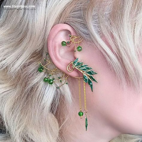 Embrace the enchanting allure of the forest with our "Verdant Aurëlinn" Elven Ear Wrap Earring, part of the Elvenwood Blossoms Collection. Crafted with meticulous attention to detail, this exquisite earpiece captures the essence of Elvish elegance. Handcrafted from non-tarnish gold-plated wire, each intricate twist and curve of the design reflects the graceful beauty of nature. Adorned with shimmering Swarovski crystals and delicately cast resin leaves, this ear wrap gleams with a mesmerizing ch Elvish Jewelry, Ear Wrap Earrings, Elf Ear Cuff, Gold Leaf Design, Anime Earrings, Fantasy Earrings, Elven Jewelry, Mystical Jewelry, Wrap Earrings