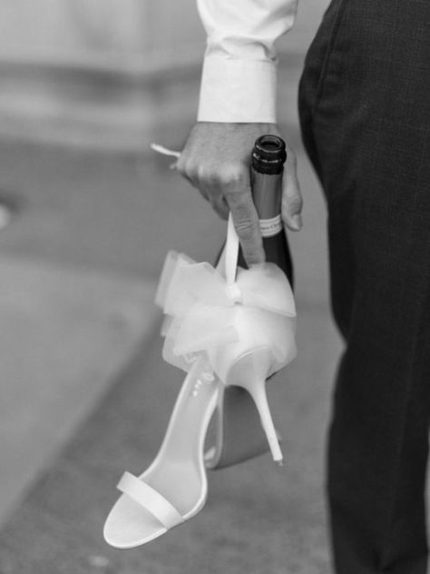 Close-up black and white shot of the groom holding the bottle of champagne and the bride’s shoes Bride Close Up Photos, Black And White Classy Wedding, Wedding Photo Ideas Champagne, Wedding Champagne Photo, Champagne Glass Engagement Photos, Farewell Poses, Engagement Photos With Champagne Bottle, Champagne Photos, Champagne Toast Engagement Photos