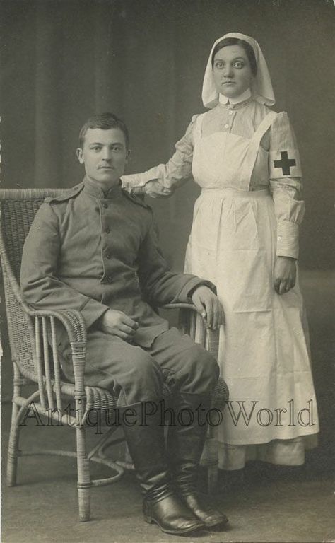 Vintage portrait of a nurse dressed in a high-collared pinstriped uniform with a pinafore and veil standing next to a seated soldier wearing a Great War uniform, watermarked Antique Photo World. Nurse And Soldier, Ww1 Nurse, Medical Clothing, Vintage Nursing, Red Cross Nurse, Tea Merchant, Nursing History, Nursing Board, Vintage Nurse