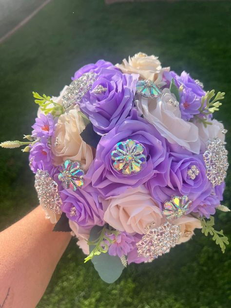 Handmade Quinceañera Bouquet/ Wedding. With Lilac and Ivory Roses. Finished off with Iridescent brooches. *Please note brooches can change in style due to availability.* Decor / color combinations can be changed upon request. {This is a made to order Bouquet} Quinceanera Bouquet Purple, Purple Quince Ramo, Quince Bouquet Purple, Iridescent Bouquet, Garden Quince, Lilac Quince, Gold Quince Dress, Xv Ideas, Tangled Wedding