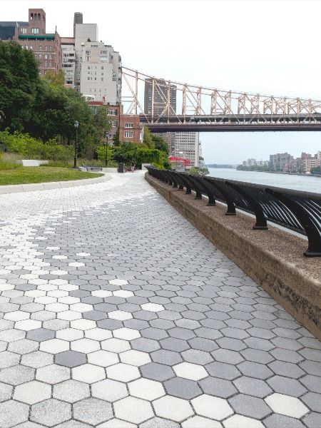 A promenade between two existing parks overlooks the East River and Queensboro Bridge in New York. Conscious of the negative impacts of stormwater runoff, permeable pavers were used in the design and create a unique gradient paving pattern with Unilock Permeable Hex / City Park Paver in three different colors. The color gradient flows along the promenade creating curves that mimic the adjacent river. #landscapearchitecture #geometricpaving Paving Design Landscape, Paving Pattern Landscape, Pavement Design Paving Pattern, Parking Pavers, Simple Concrete Patio, Pavers Pattern, Paver Block Design, Pavement Pattern, Brick Pavement