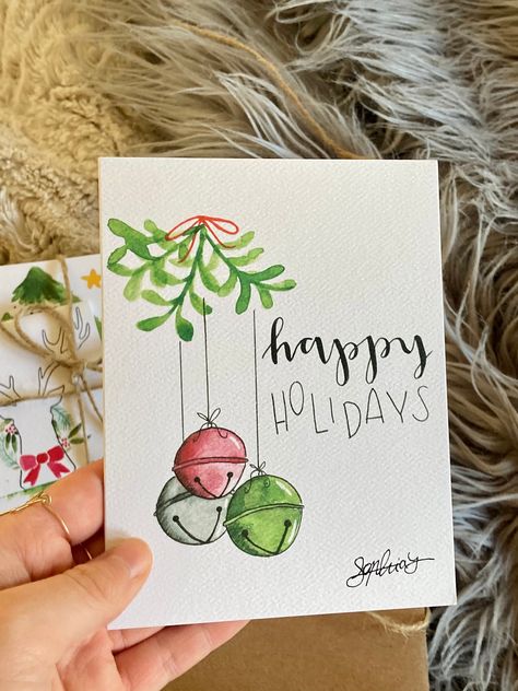 'Jingle Bells Happy Holidays' Watercolor Greeting Card | Sophia Lavrov ~Blank printed card + brown paper bag envelope + cello sleeve ~The best way to spread Christmas cheer is through greeting cards! ~Sophia Lavrov's original watercolor artwork, adorned with calligraphy ~ Printed card, hand-packaged ~Instagram: @sophialavrovdesigns ~Website: sophialavrovdesigns.com Christmas Cards Christmas Tree, Watercolor St Patricks Day Cards, Christmas Cards To Draw, Christmas Water Coloring Ideas, Christmas Watercolors Easy, Watercolor Christmas Lights, Christmas Cards Watercolor Simple, Watercolor Art Christmas Cards, Christmas Cards Watercolor Ideas