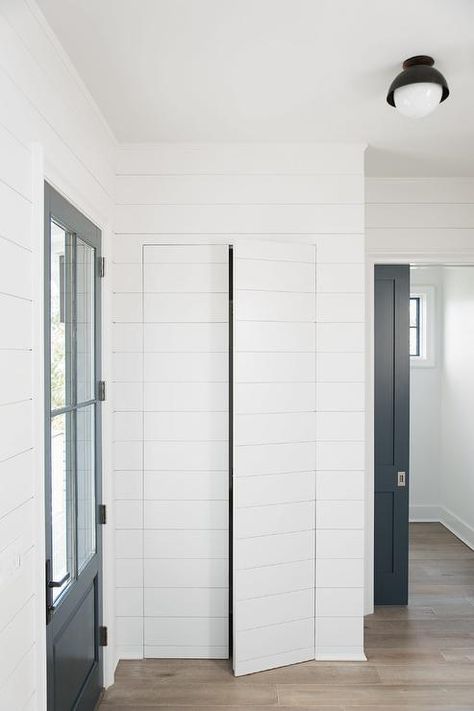 A foyer closet is concealed behind white shiplap jib doors positioned adjacent toa. black door with 4 glass panels. Cortney Bishop Design Jib Door, Secret Door Ideas, Cortney Bishop, Foyer Closet, Hidden Doors In Walls, Diy Doors, Staining Wood Floors, Gray Stained Wood, Hidden Closet