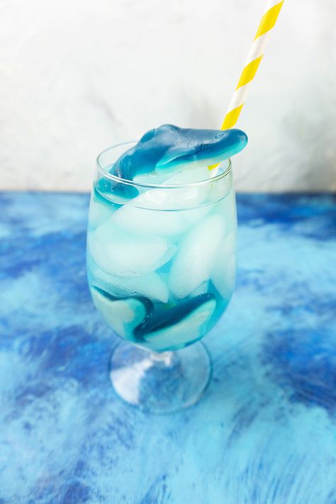 This refreshing summer drink is perfect for kids. Blue Gatorade and 7-Up are mixed together with some ice and shark gummies to look just like the ocean. Make this fun, easy DIY drink recipe today!#sharkweekrecipes #sharkfizzydrink #kidfriendlydrink #mocktailrecipes #sharkweek Gummy Bear Cocktail Recipe, Shark Gummies, Shark Week Recipes, Blue Gatorade, Gummy Sharks, Ocean Stuff, Kid Friendly Drinks, Blue Drinks, Diy Drinks