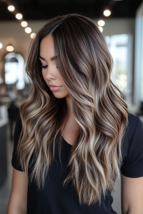 Woman with long wavy hair and soft highlights in a modern salon. Brunette With Shadow Root, Brown Balayage With Ashy Tones, Side Part Balayage Brunettes, Winter Blonde Highlights Brunettes, Fall Hair Colours For Brunettes, Balayage Hair Color For Black Hair, Hair Balayage Brunette To Blonde, Rich Balayage Brunettes, Ash Brown With Blonde Balayage