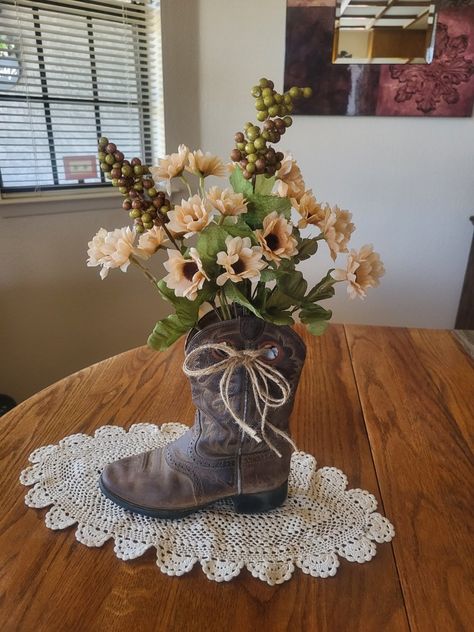 This is my 2nd decorated cowboy boot with flowers. Makes a nice rustic western look. The twine bow sets it off nicely. I stuffed the boot with heavy brown paper to keep it looking full and not tipping over. The doily gives it a nice country look. I love to upcycle/repurpose items. Cowboy Boots Flower Arrangement, Cowboy Boots Decor Ideas, Boot Vase Centerpiece, Crafts With Cowboy Boots, Cowboy Boot Repurpose Ideas, Repurpose Old Cowboy Boots, Country Flower Arrangements Rustic Decor, Decorating With Cowboy Boots, Cowgirl Boot Flower Vase