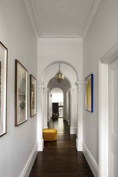 Magnificent arches frame the view from the front door through to the new back section of the home. The white walls are painted Dulux Snowy Mountains Half in low sheen with frames and skirting boards in semi-gloss. American oak floorboards, sourced and stained to match the originals. Normann Copenhagen 'Circus' pouf in Yellow from Stem Online. Vintage prints on left, framed by owners. Blue-framed artwork by David Shrigley. Victorian Terrace Hallway, White Hallway Ideas, Victorian Entryway, Renovated Victorian House, Victorian Entrance, Victorian Style Interior, Roof Section, Victorian Terrace Interior, Renovated Victorian