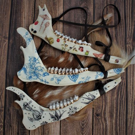 Deer Jawbone | Wall hanging decor real bone painted skull deer animal teeth gold vulture culture delft cottage core tattoo oddities tooth Each of these deer jawbones have been adorned with a variety of vintage-style illustrations, perfect for any naturalist or entomology lover. Jawbones are from whitetail deer, naturally found and nature-cleaned, then gently sanitized and whitened. The back has an attached triangle hanger as well as a deerskin leather lace, ready for wall installation. These pie Animal Bone Projects, Painted Deer Jaw Bone, Bone Crafts Ideas, Painted Bones Art, Animal Jaw Bone Art, Deer Bone Art, Animal Bone Decor, Animal Bone Crafts, Deer Hide Decor