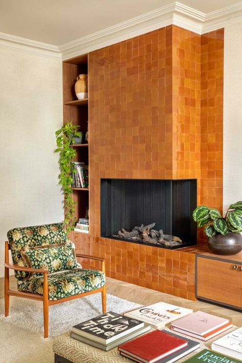 A tile-covered fireplace surround makes a bold statement in this living room. Brick Fireplace In Living Room, Mid Century Electric Fireplace, Fireplace Next To Stairs, 1970 Fireplace, Mcm Fireplace Wall, Cover Up Brick Fireplace, Midcentury Fireplace Ideas, Terracotta Tile Fireplace, Fireplace 70s