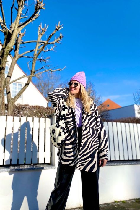 Girl with blond hair wearing a patterned faux fur bag, zebra print shacket, lilac beanie, Ray-Ban sunglasses, lilac sweatshirt, faux leather pants and chunky chelsea boots. Lilac Sweatshirt, Shacket Outfit Women, Shacket Outfit, Faux Fur Fashion, Chunky Chelsea Boots, Faux Fur Bag, Hand Purse, Fur Bag, Spring Fashion Outfits